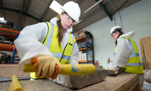 Two people in a workshop, shaping lead using lead beaters