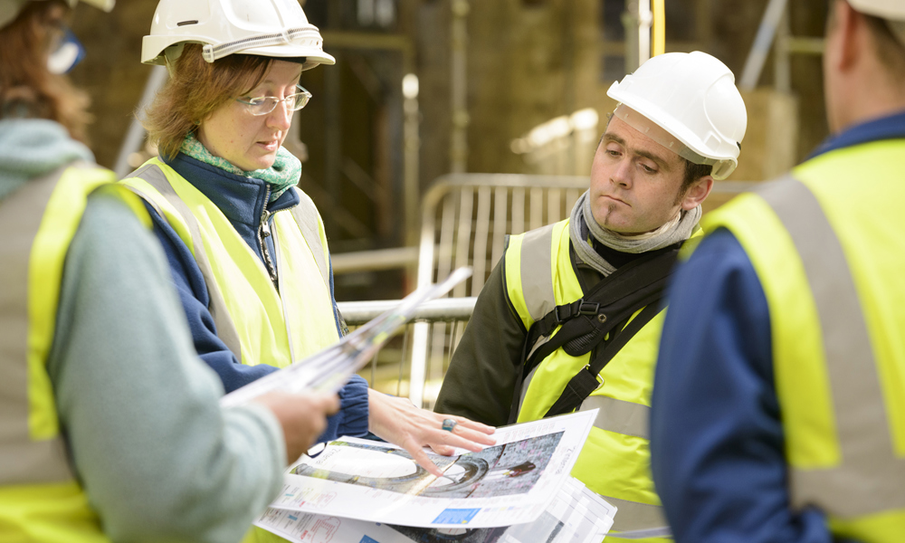 People wearing hardhats looking at paper plans