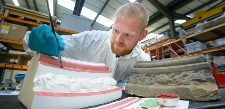 Someone painting a piece of decorative stonework for a building