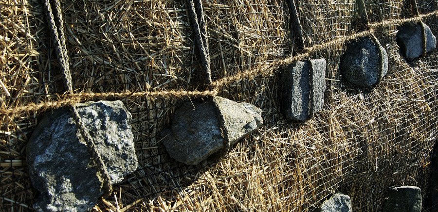 A thatched roof being held down with stones and netting