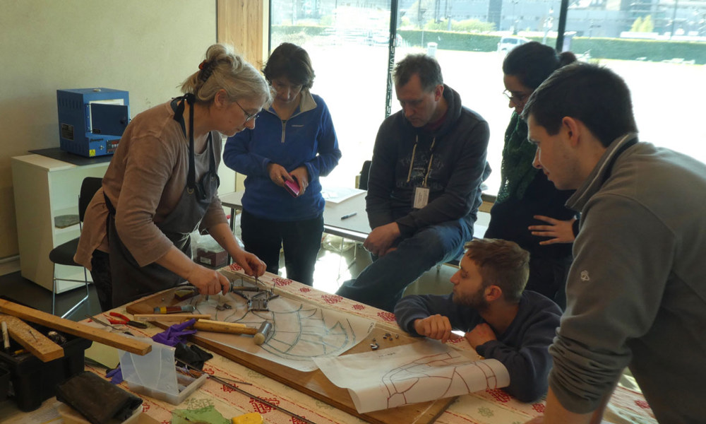 A person demonstrating how to make a stained glass window to a group of people